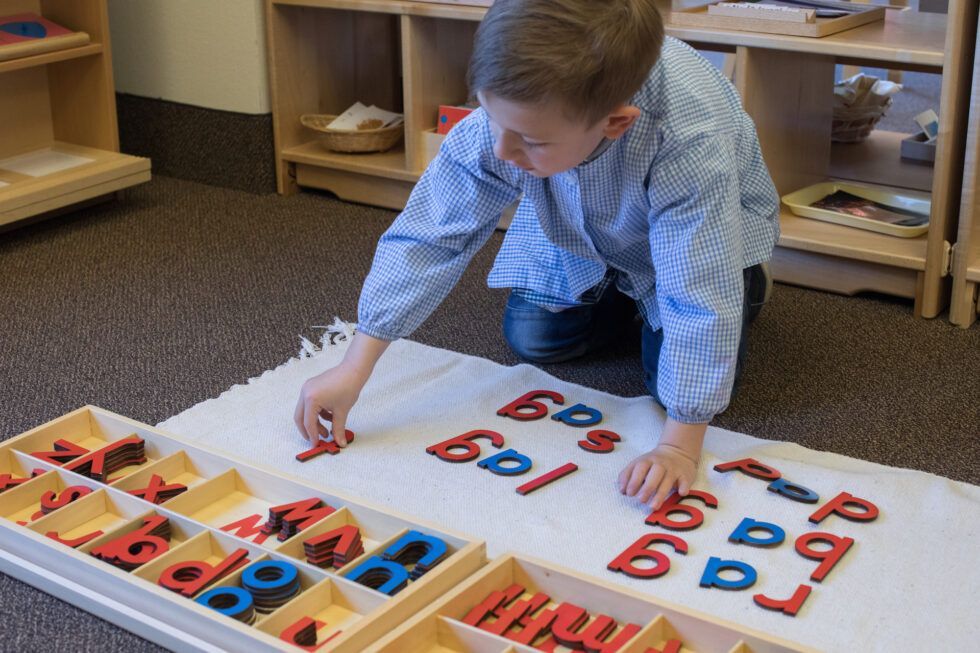 Montessori child is working with letters and numbers on the floor