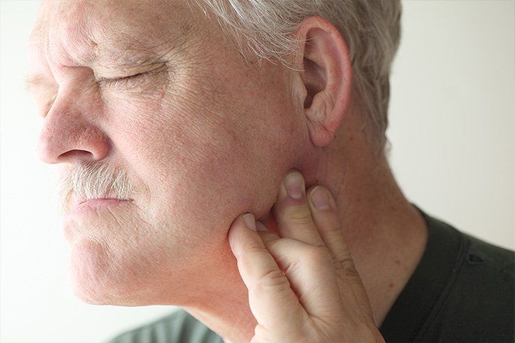 An older man is holding his mouth in pain because of a toothache.