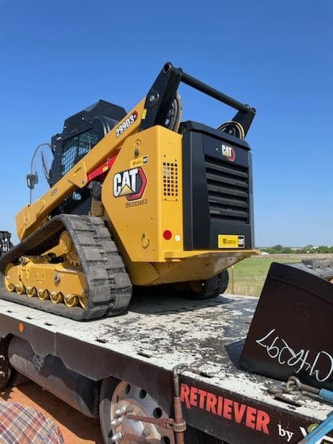 A cat tractor is sitting on top of a tow truck
