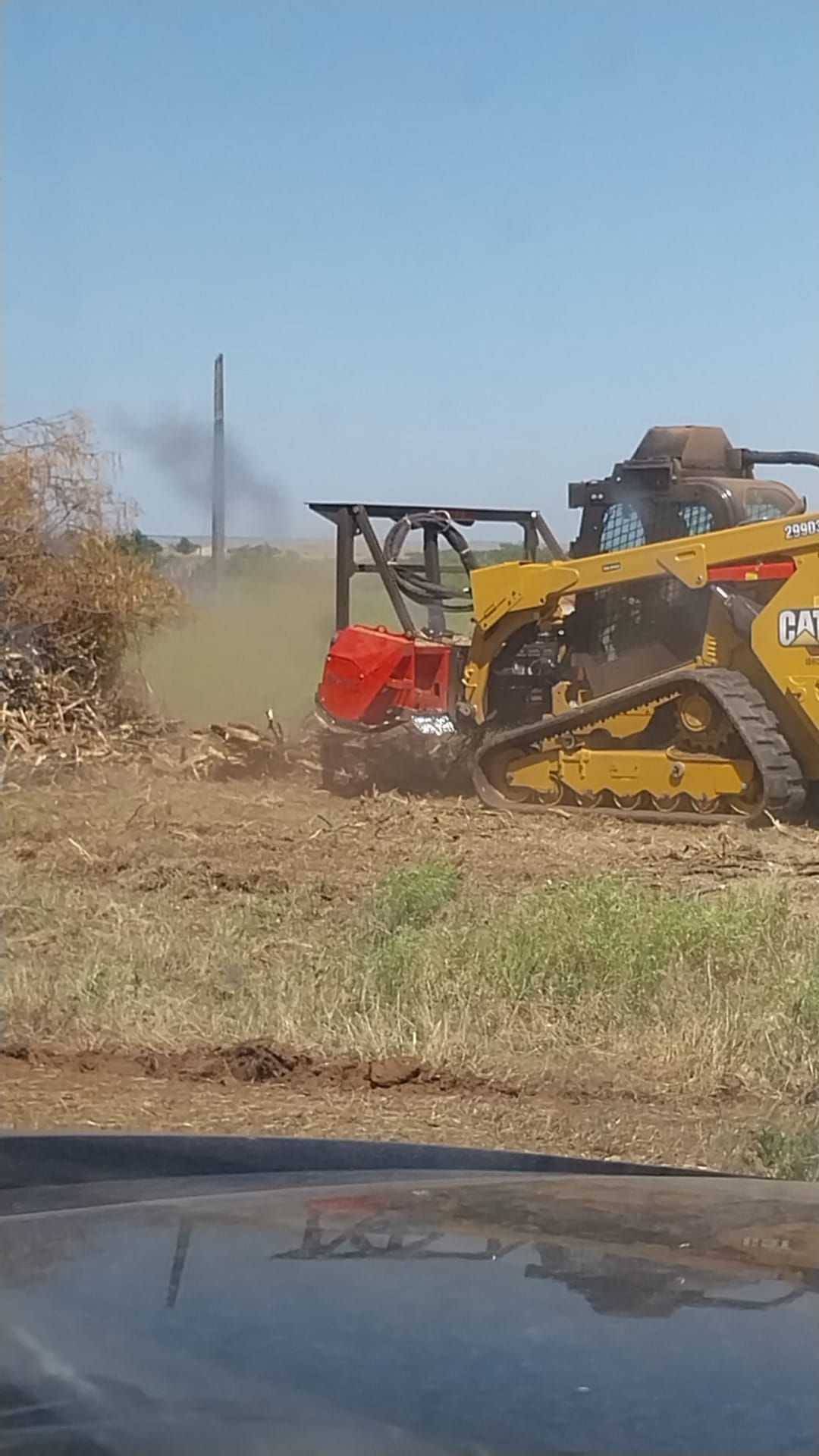 A bulldozer is cutting a tree stump in a field.