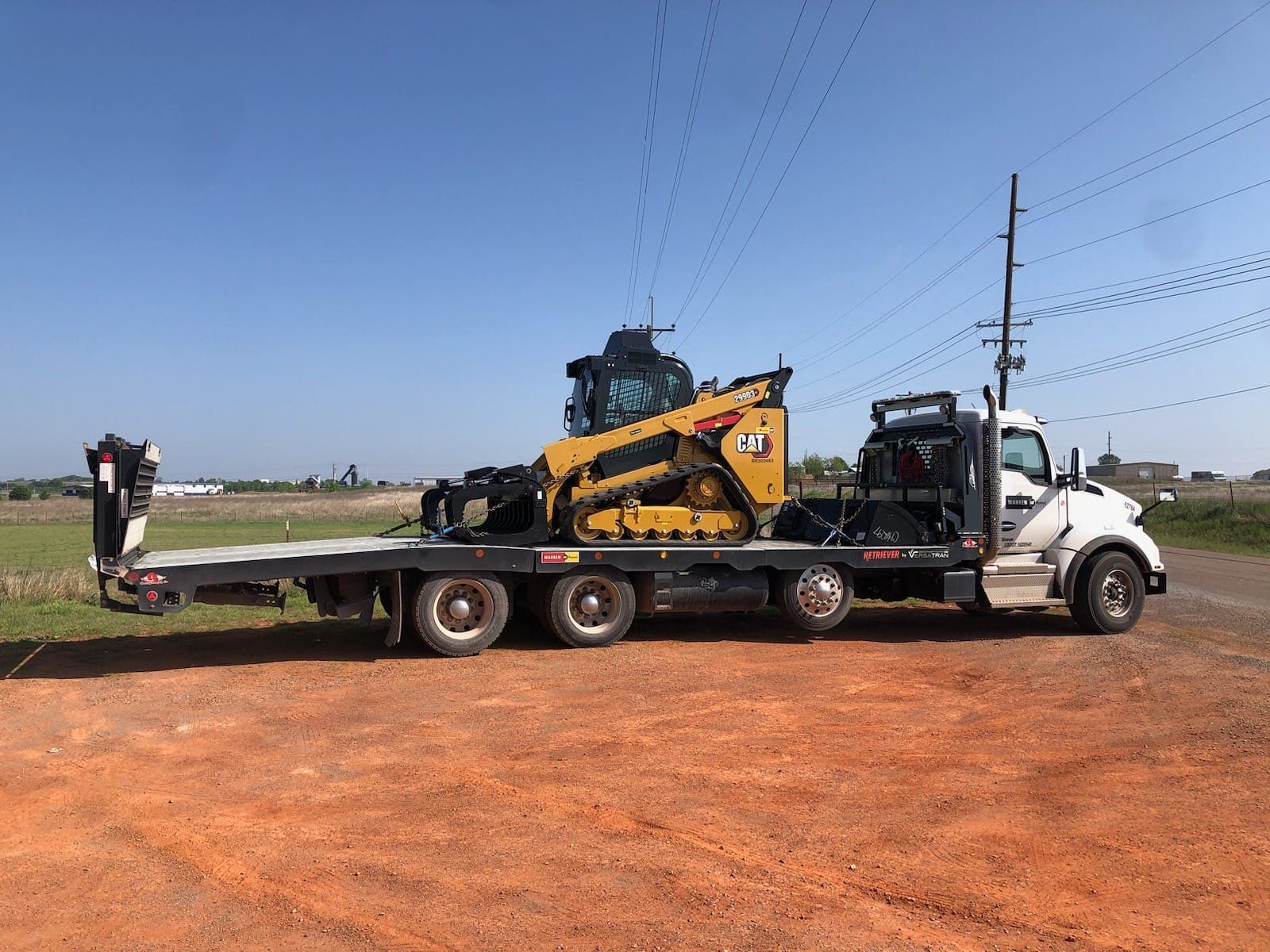 A tow truck is carrying a bulldozer on a flatbed trailer.