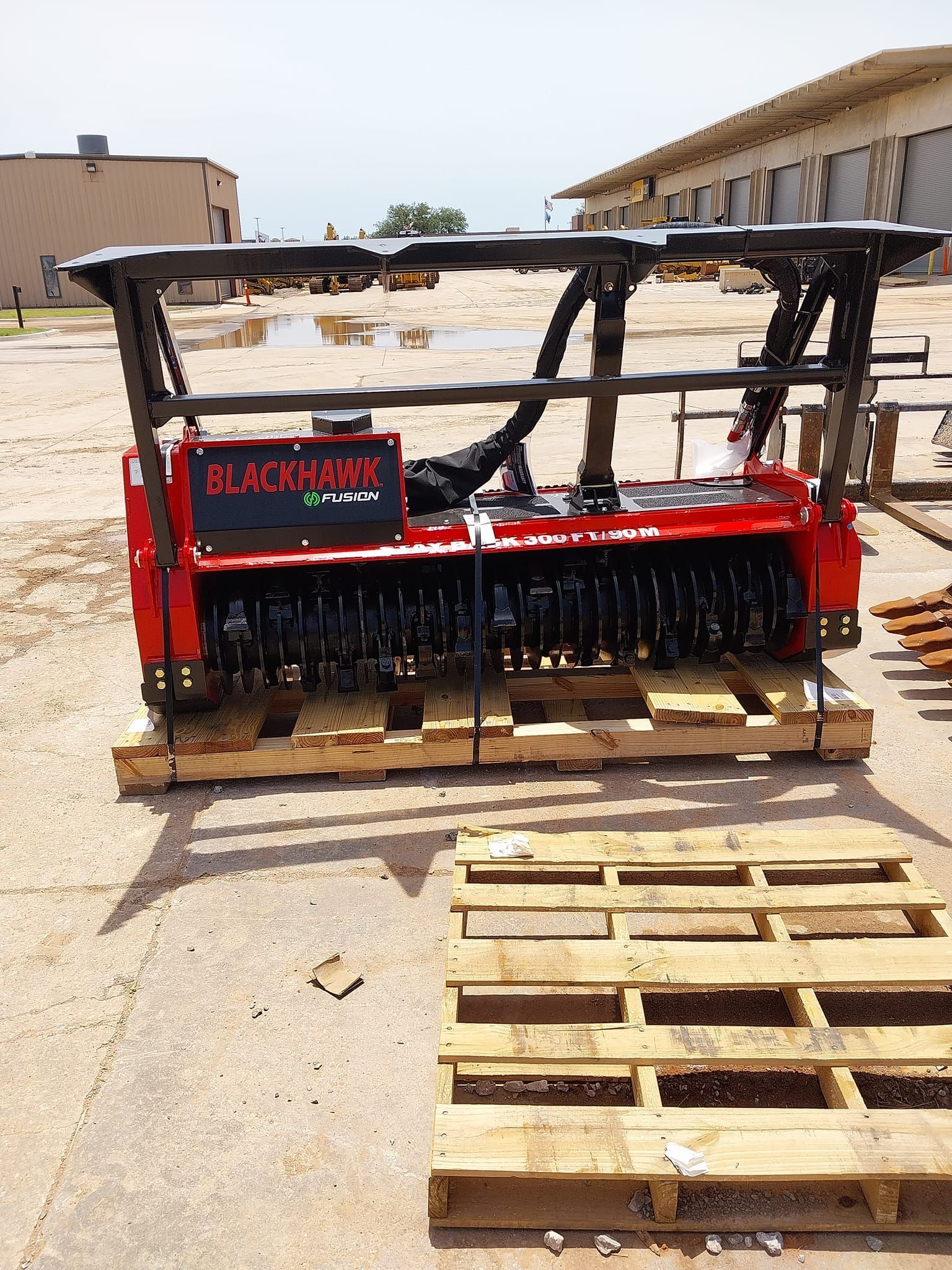 A red and black machine is sitting on a wooden pallet.