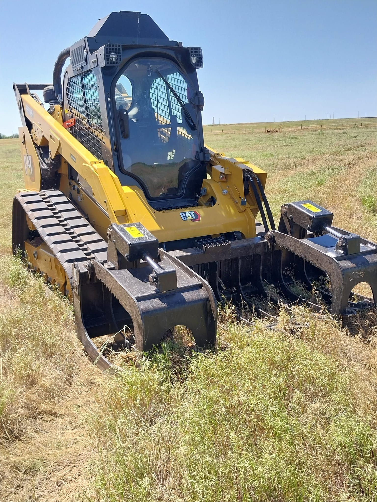 A yellow and black bulldozer is sitting in the middle of a grassy field.
