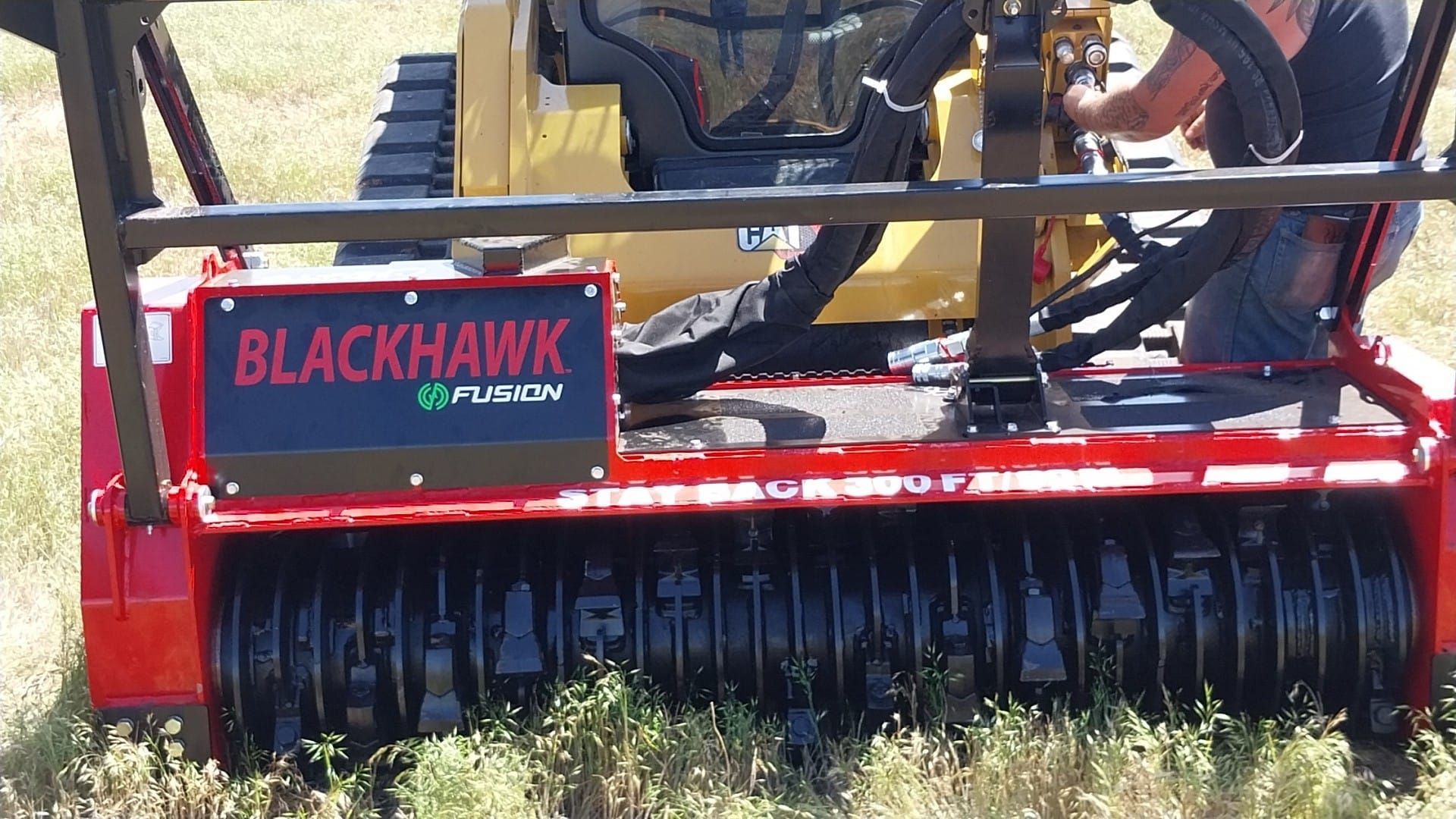 A man is working on a blackhawk tractor in a field