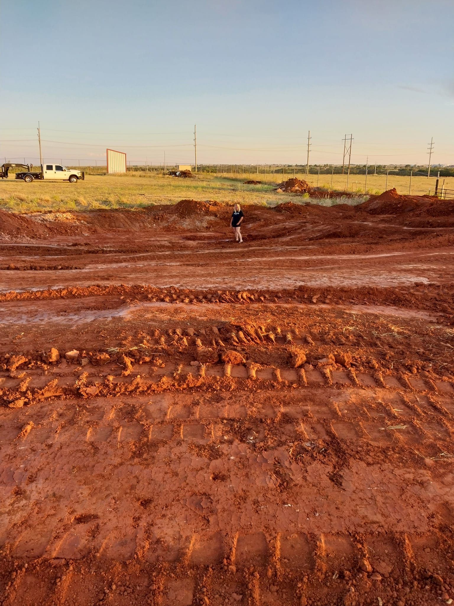 A man is standing in the middle of a muddy field.