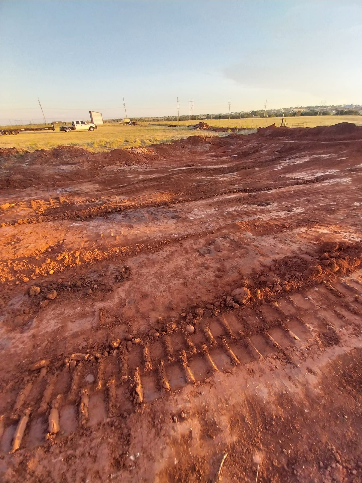 A large dirt field with tractor tracks in it.