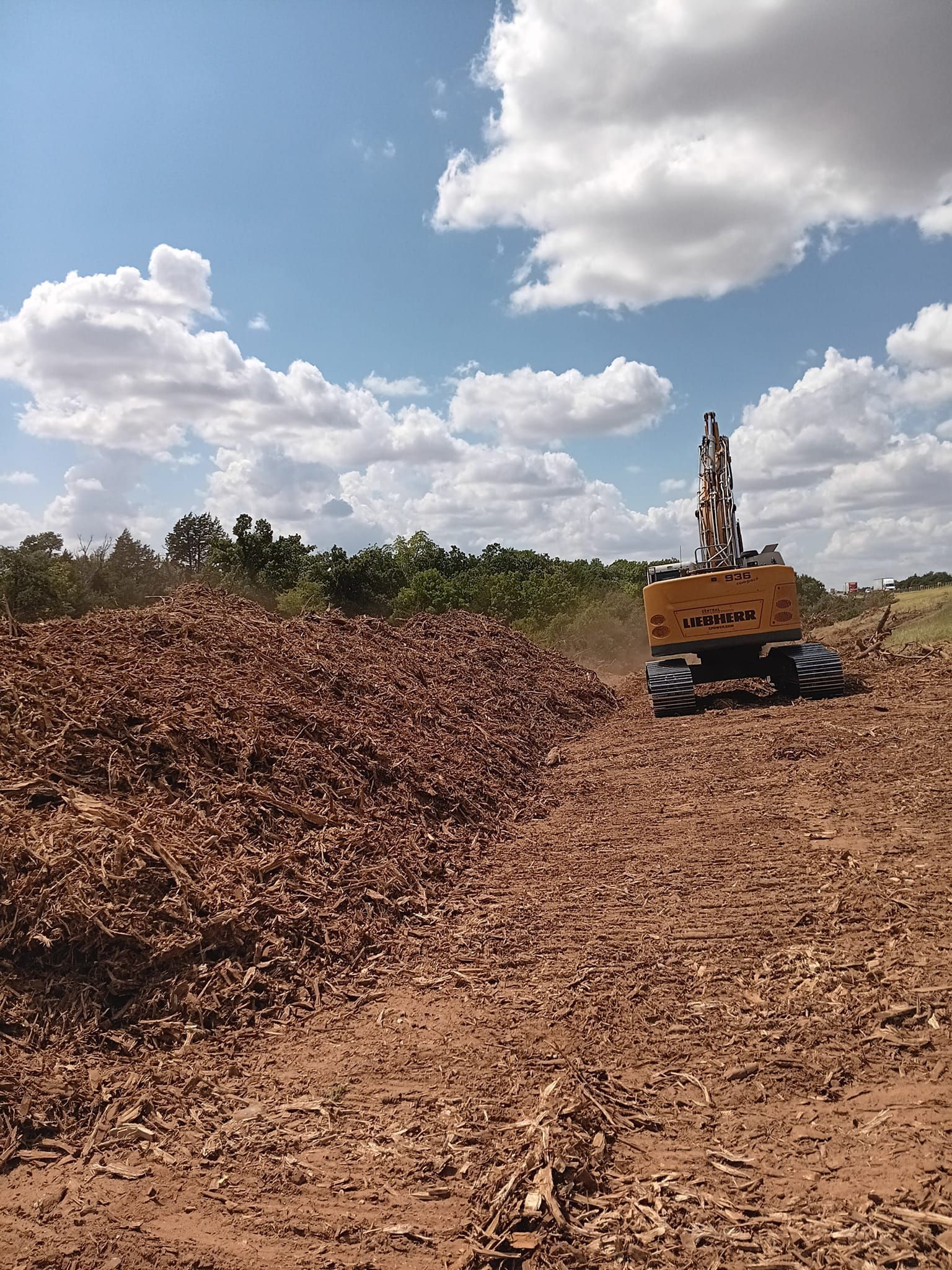 A yellow excavator is driving through a pile of dirt.