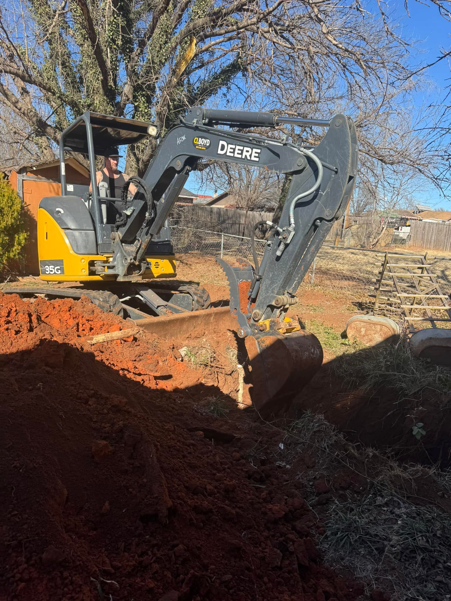 A deere excavator is digging a hole in the dirt.