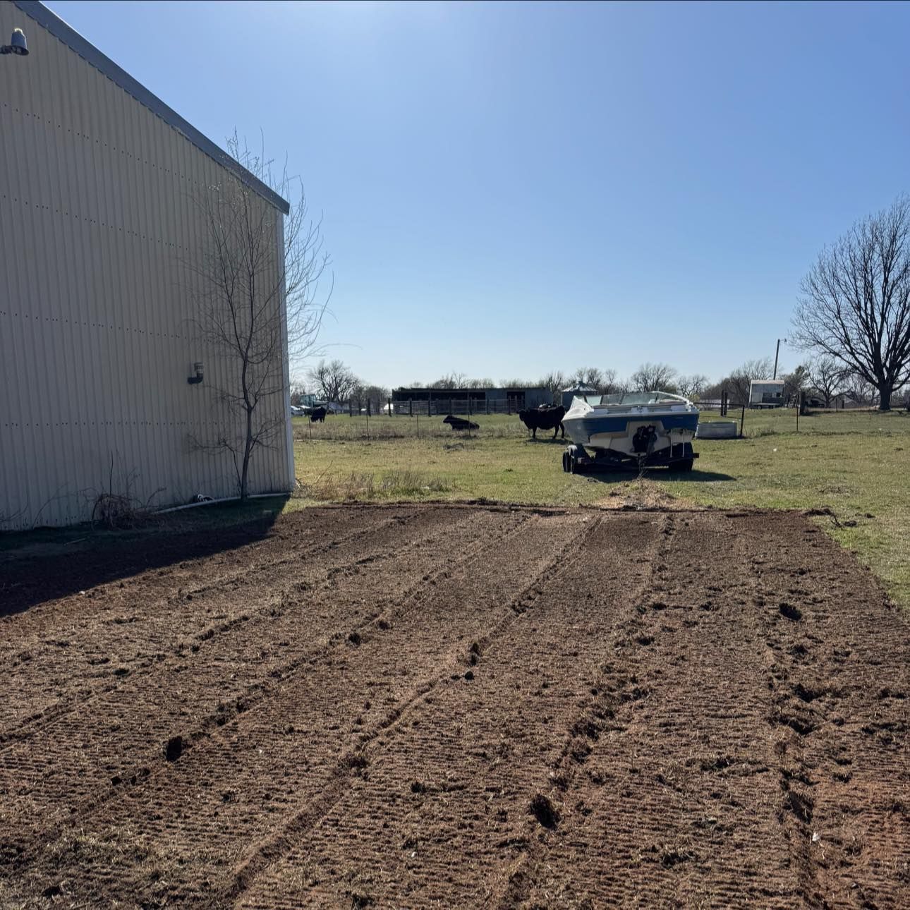 A boat is parked in a field next to a barn