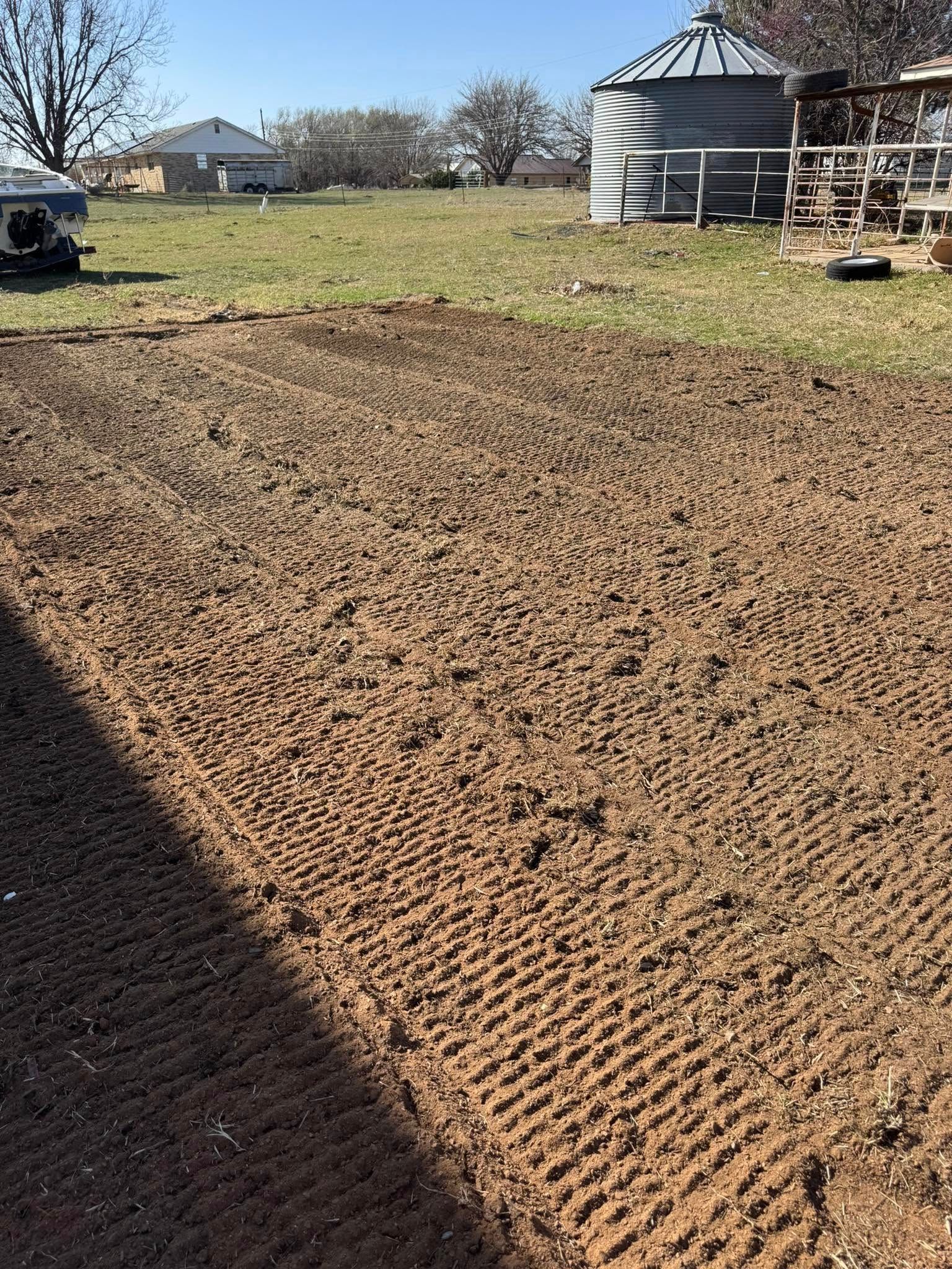 A large dirt field with a silo in the background.
