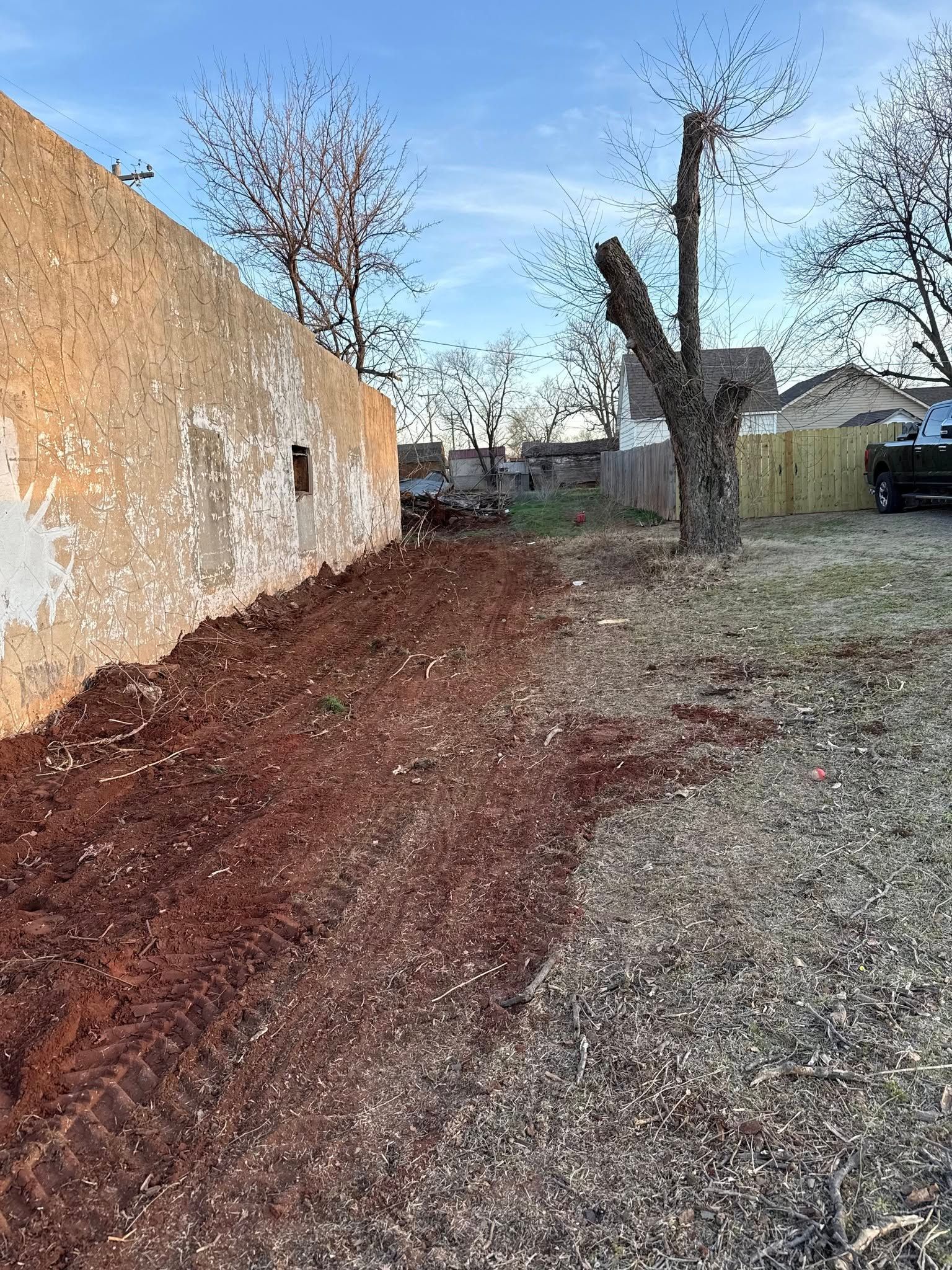 A pile of dirt is sitting next to a wall in a yard.