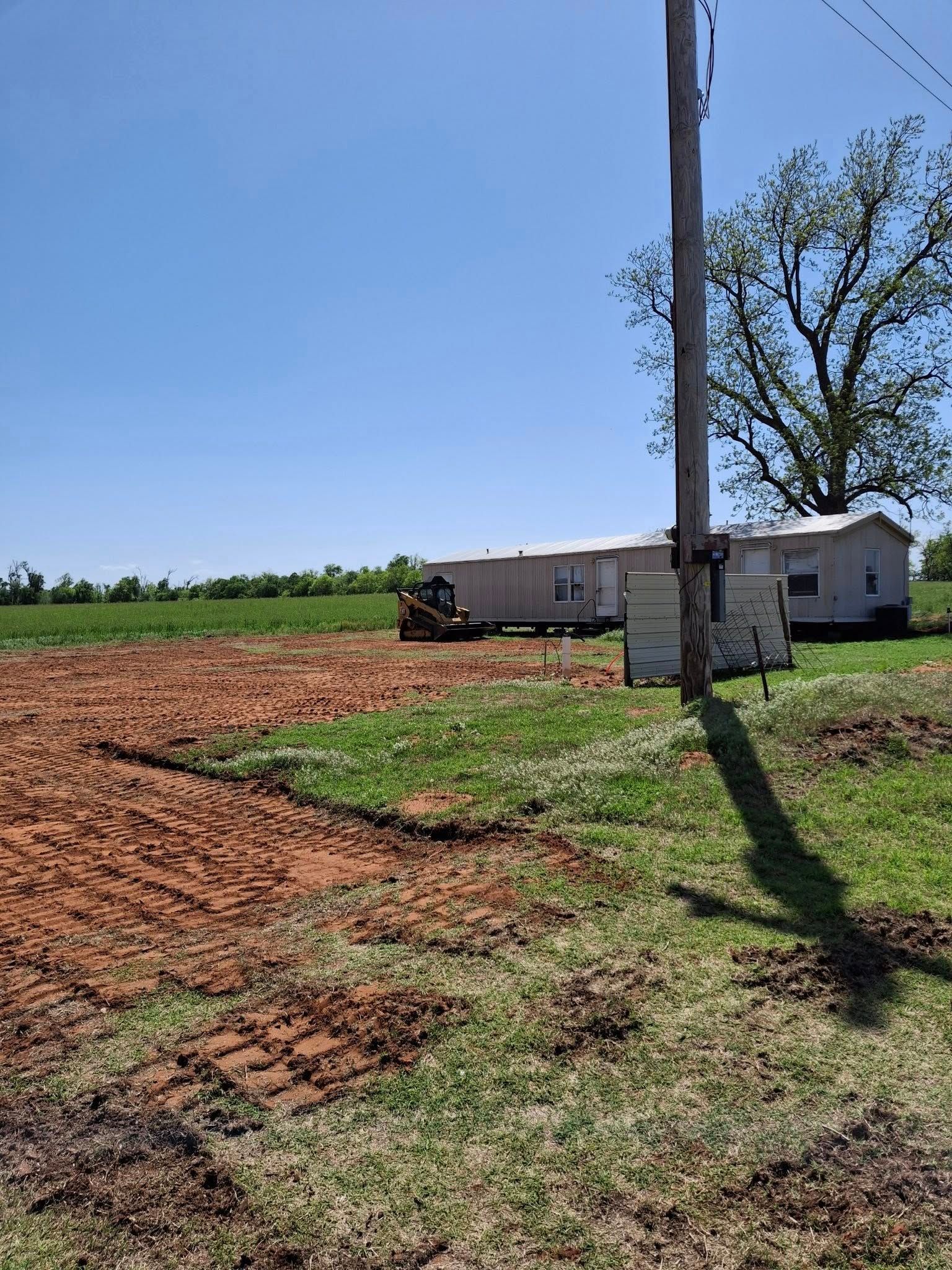 A house is sitting in the middle of a field next to a train.