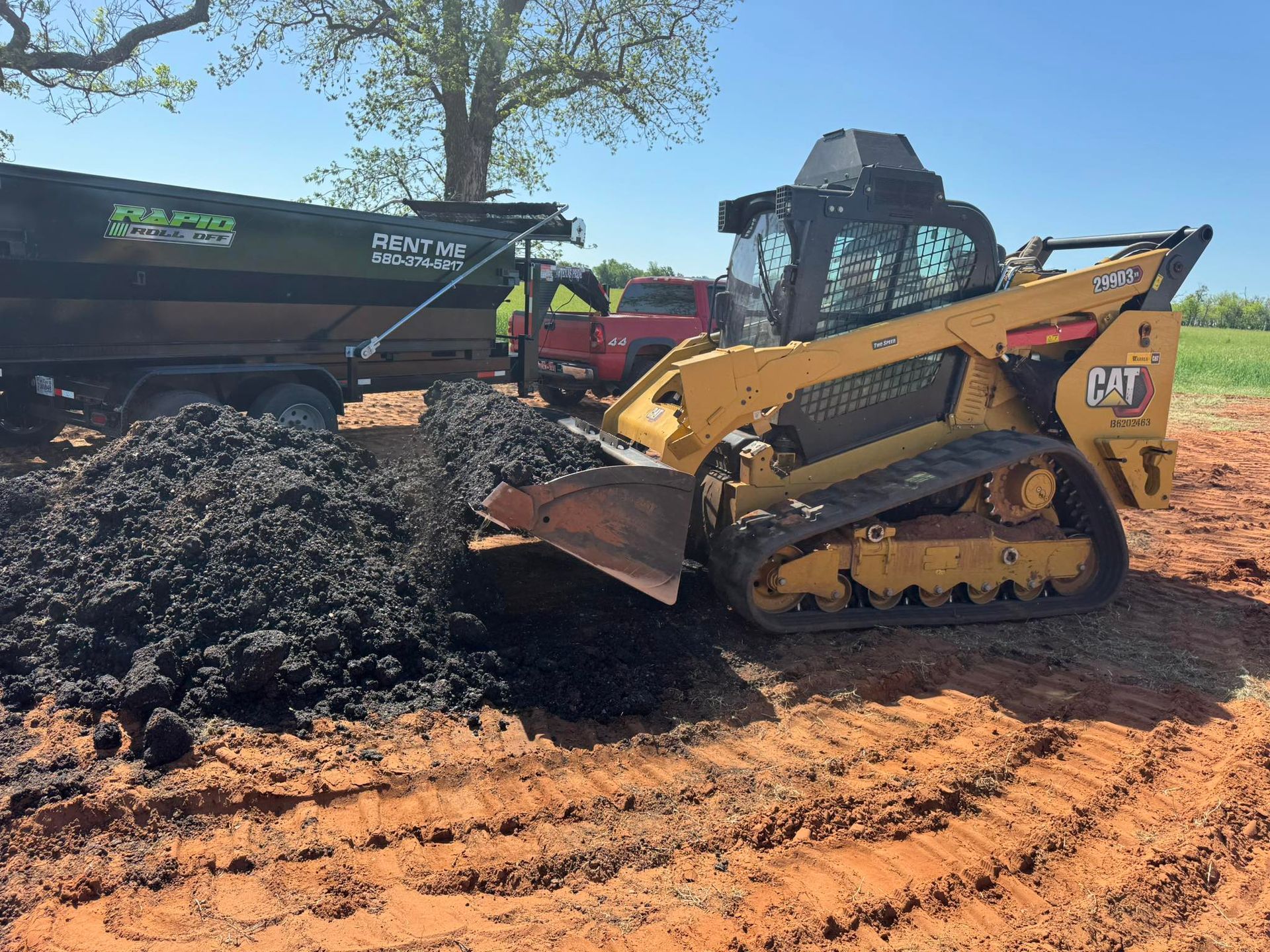 A bulldozer is loading dirt into a dump truck.