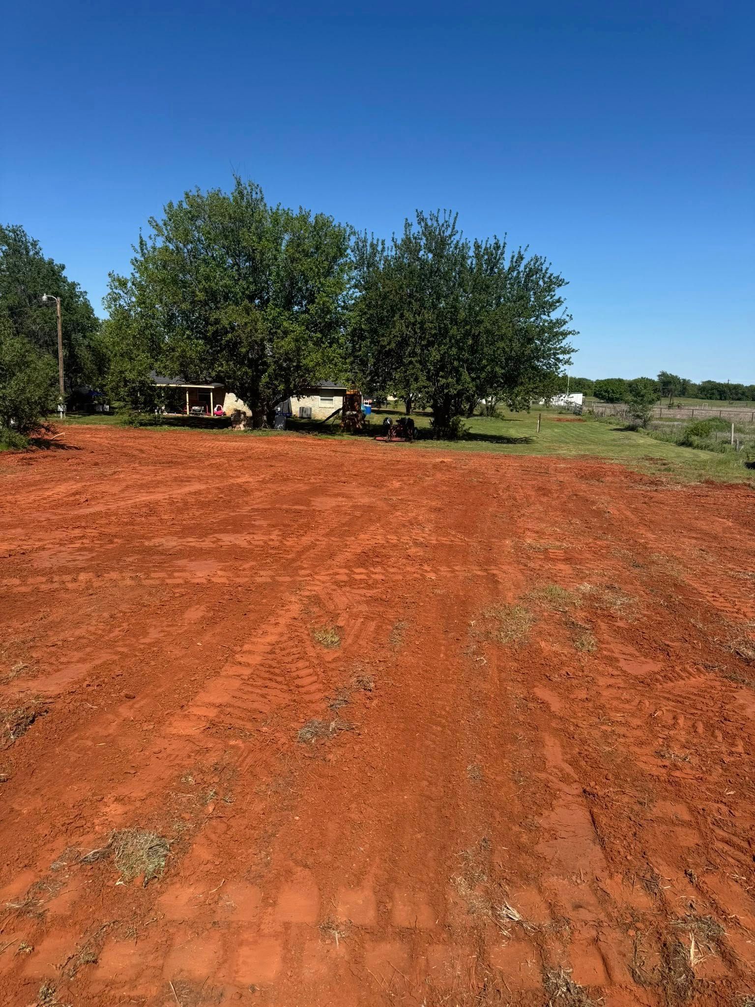 A dirt road going through a field with trees in the background.