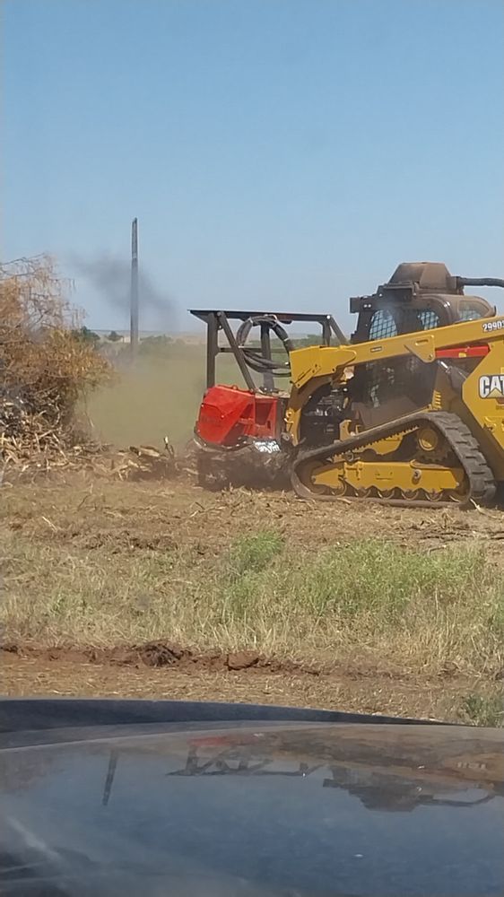 A bulldozer is loading dirt into a dump truck.