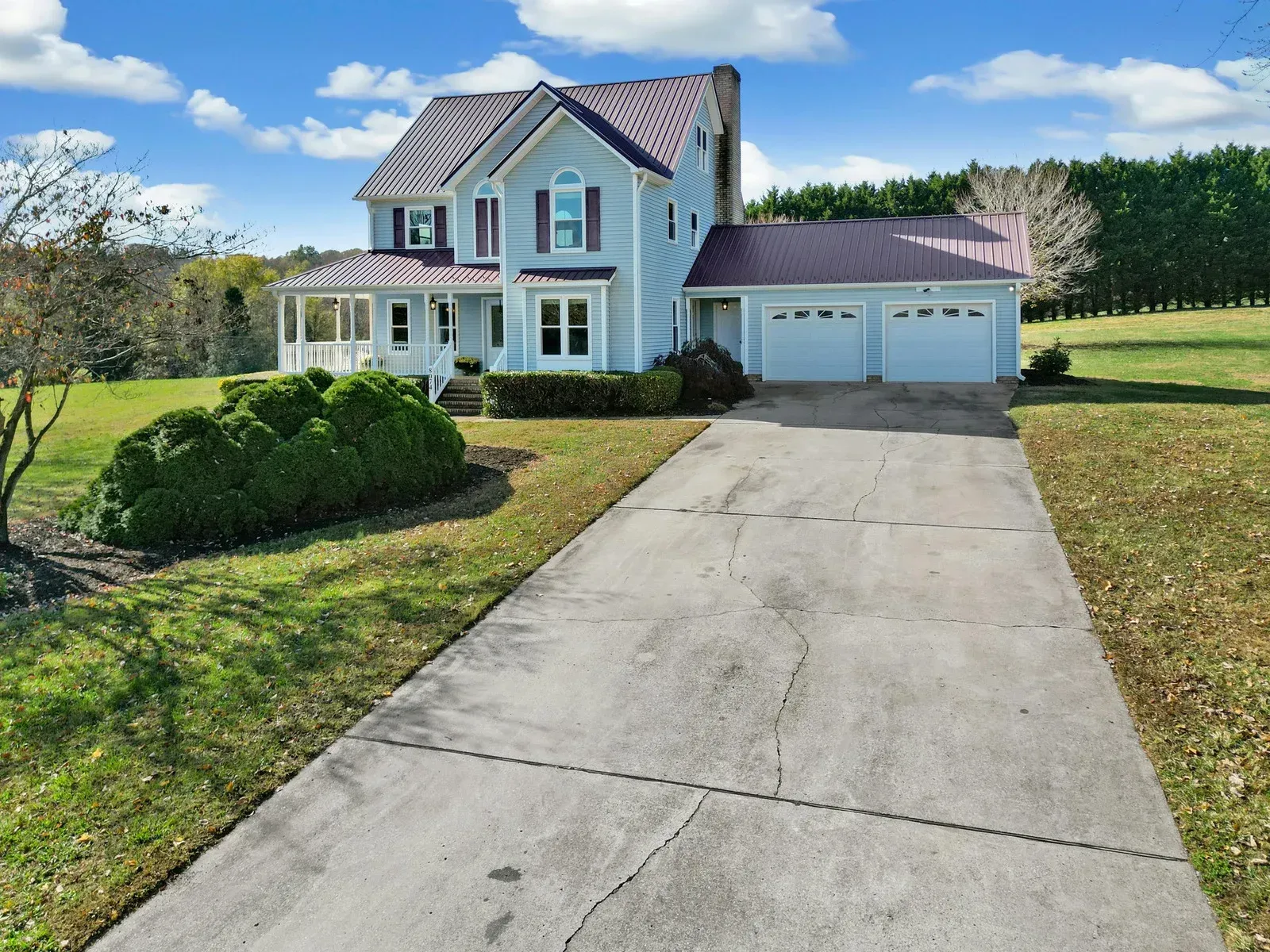 A white house with a purple roof and a driveway