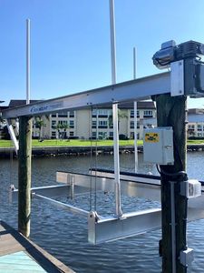 A boat lift is attached to a wooden post in the water.