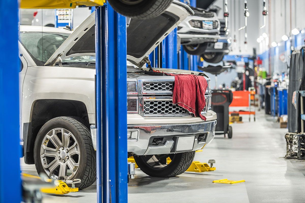 Truck in a brightly lit auto shop, on a lift. Other vehicles are also on lifts.