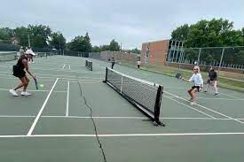 A group of people are playing tennis on a tennis court.