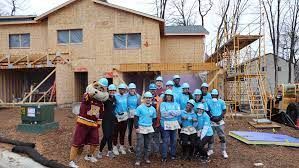 A group of people are posing for a picture in front of a house under construction.