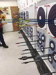 A man is standing in front of a row of archery targets.