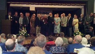 A group of people are standing on a stage in front of a crowd.