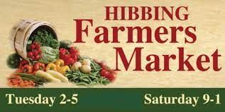 A sign for the hibbing farmers market shows a bucket of vegetables.