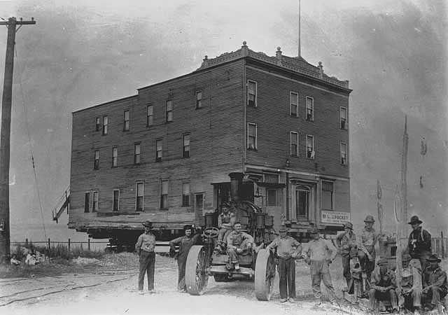 A group of men are standing in front of a large brick building.