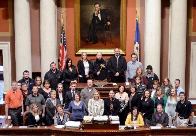 A group of people are posing for a picture in front of a painting of abraham lincoln