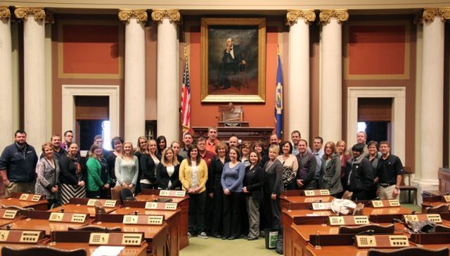 A large group of people are posing for a picture in a capitol building