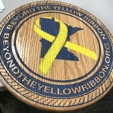 A wooden plaque with a yellow ribbon on it.