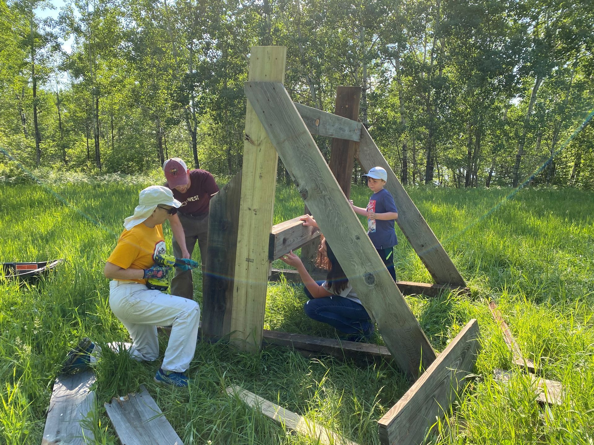 A group of people are working on a wooden structure in a field.
