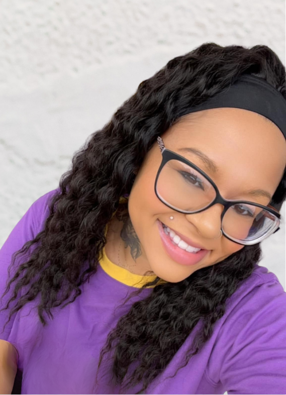 A woman wearing glasses and a headband is smiling for the camera.