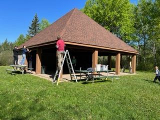A group of people are working on the roof of a pavilion.