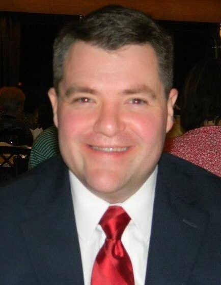 A man in a suit and tie smiles for the camera