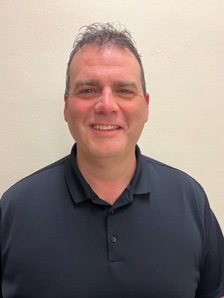 A man in a black shirt is smiling for the camera.