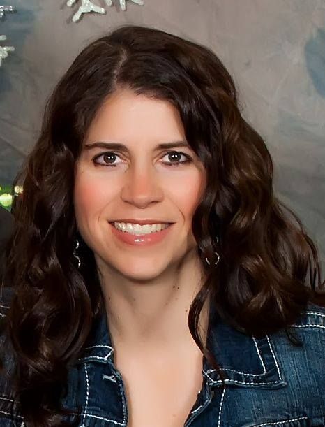 A woman in a denim jacket is smiling for the camera