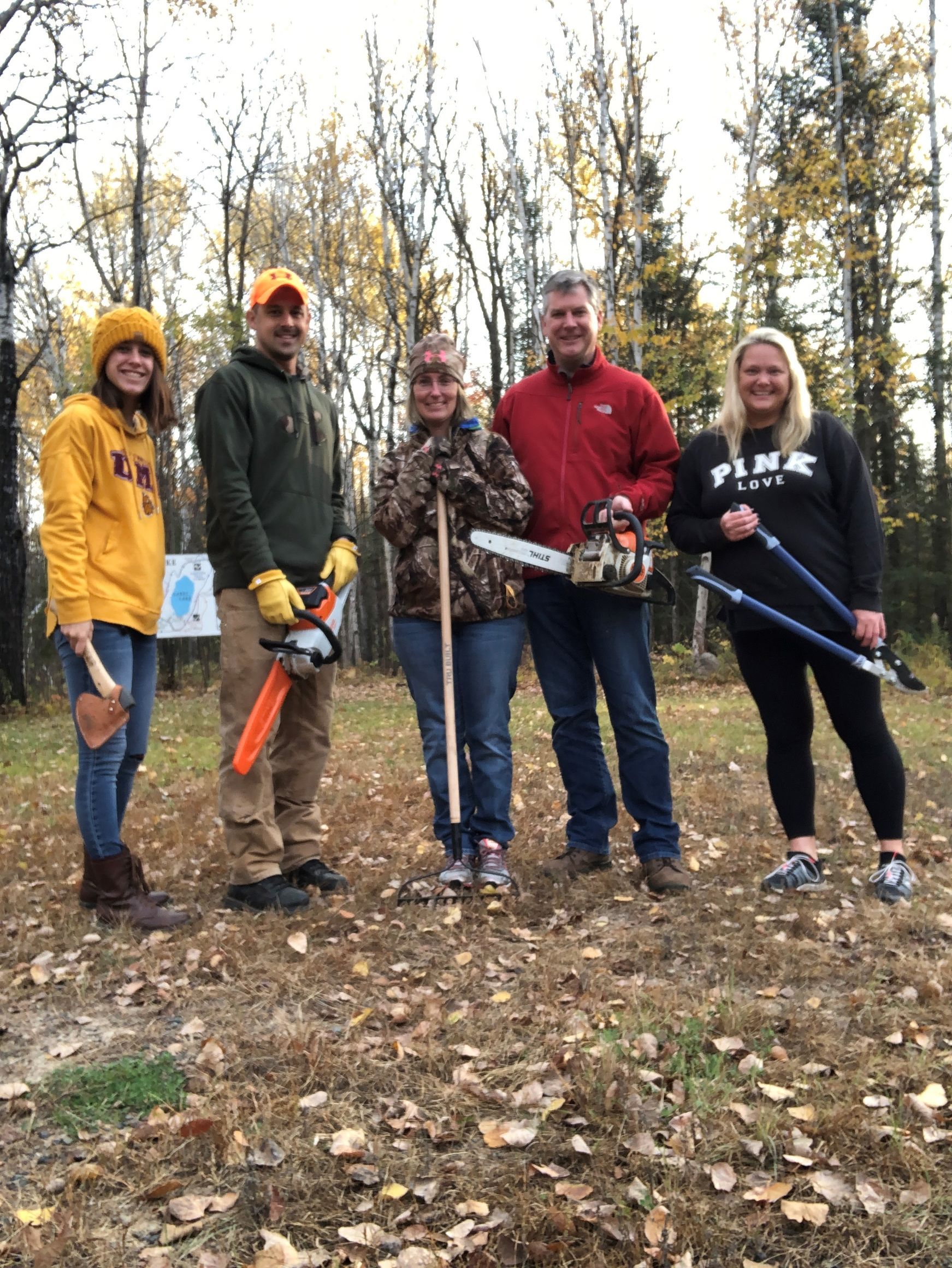 A group of people are standing in a field holding tools.