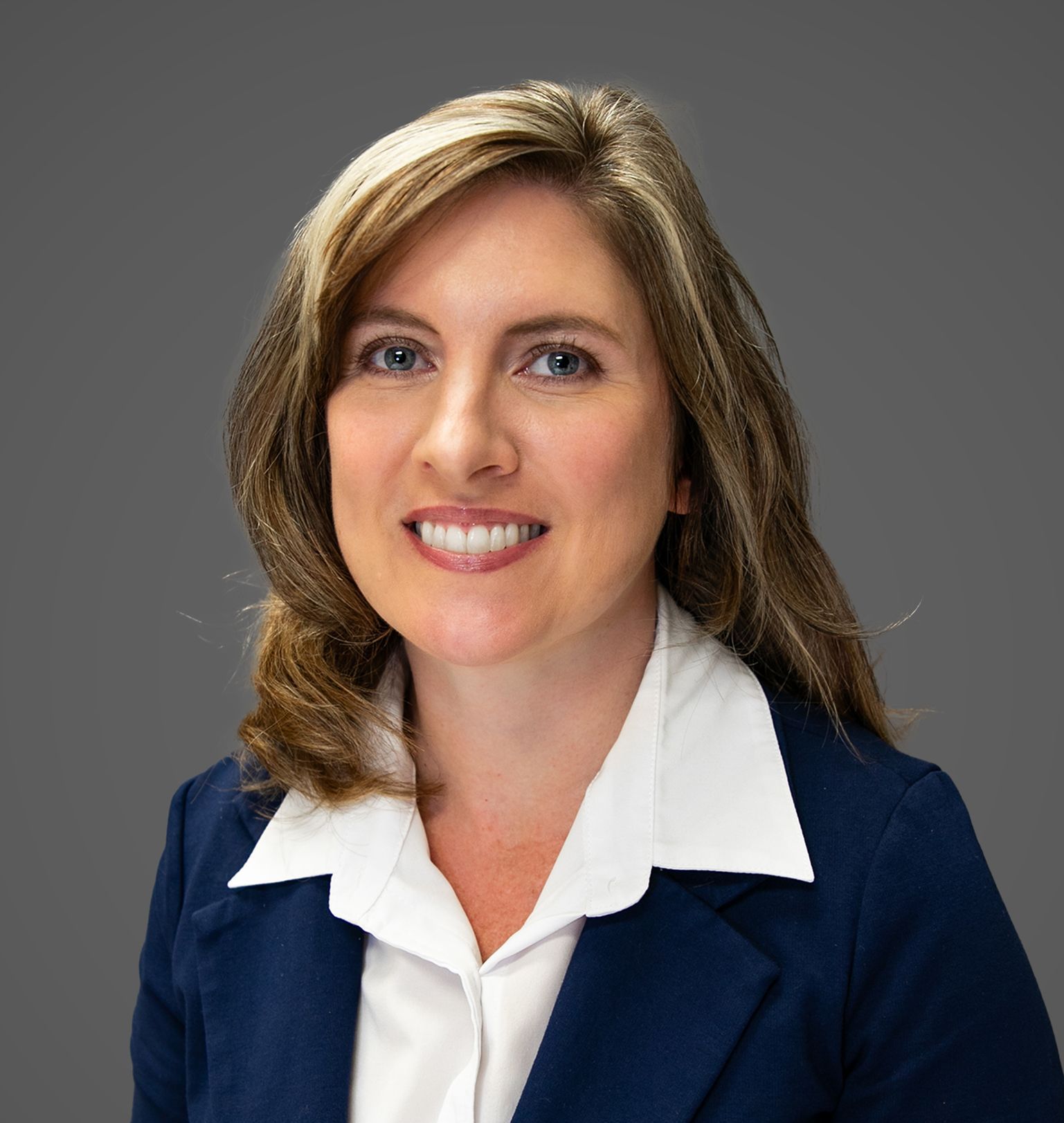 A woman in a blue jacket and white shirt is smiling for the camera.