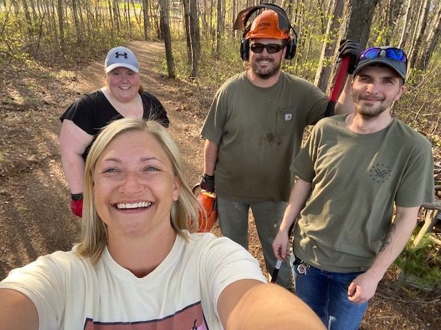 A group of people are posing for a selfie in the woods.