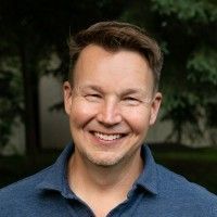 A man in a black shirt is smiling for the camera.