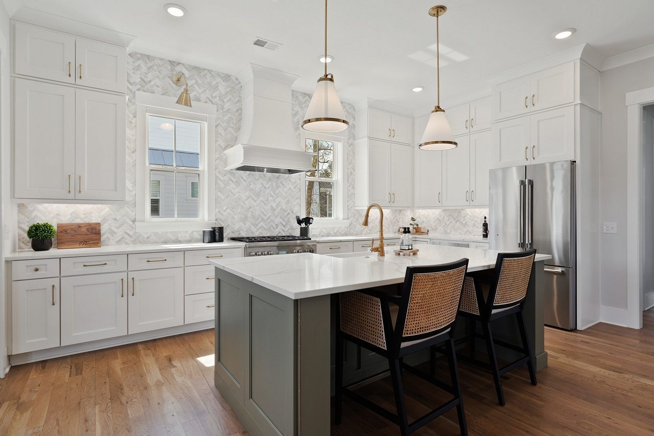 A kitchen with white cabinets , stainless steel appliances , and a large island.