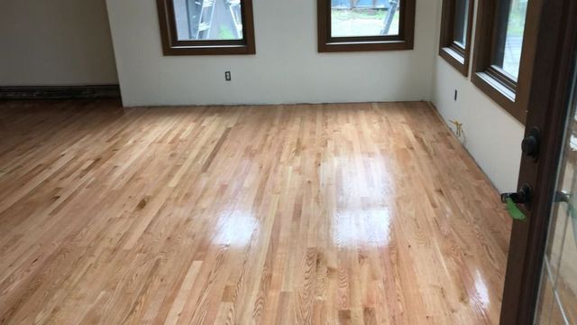 A living room with hardwood floors and two windows.
