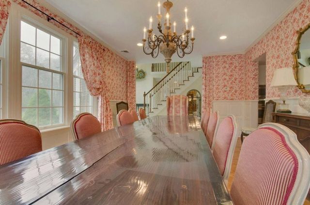 A dining room with a long table and chairs and a chandelier.