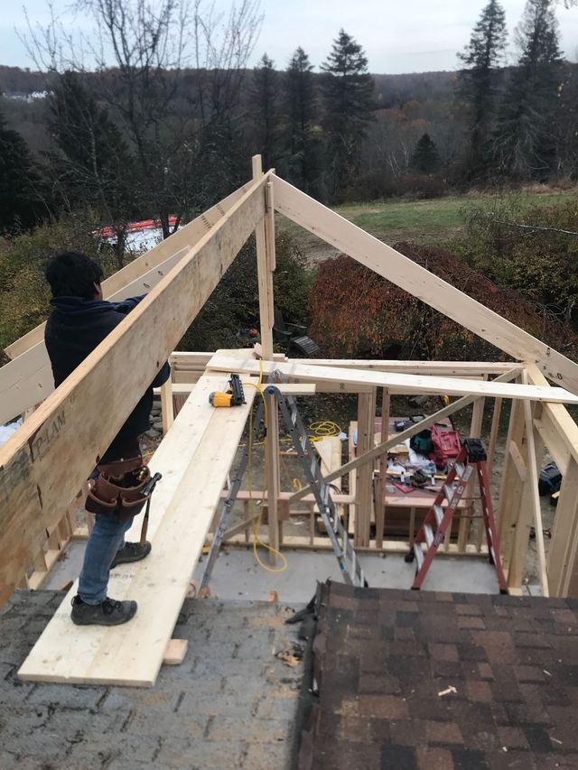 A man is standing on a wooden beam on top of a wooden structure.
