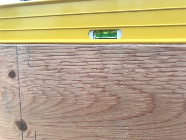 A yellow level is sitting on top of a wooden surface.