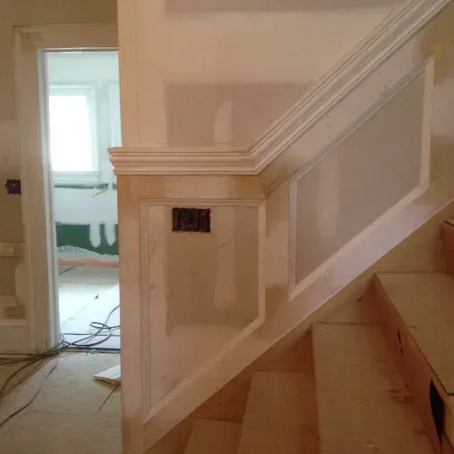 A staircase with a white railing is under construction in a house.