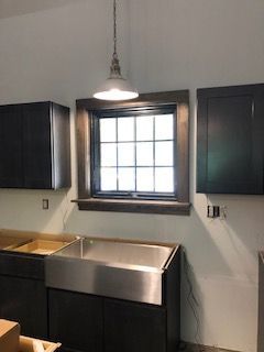 A kitchen with a sink , cabinets , and a window.