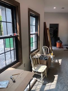 A room with a table , chairs , and two windows.