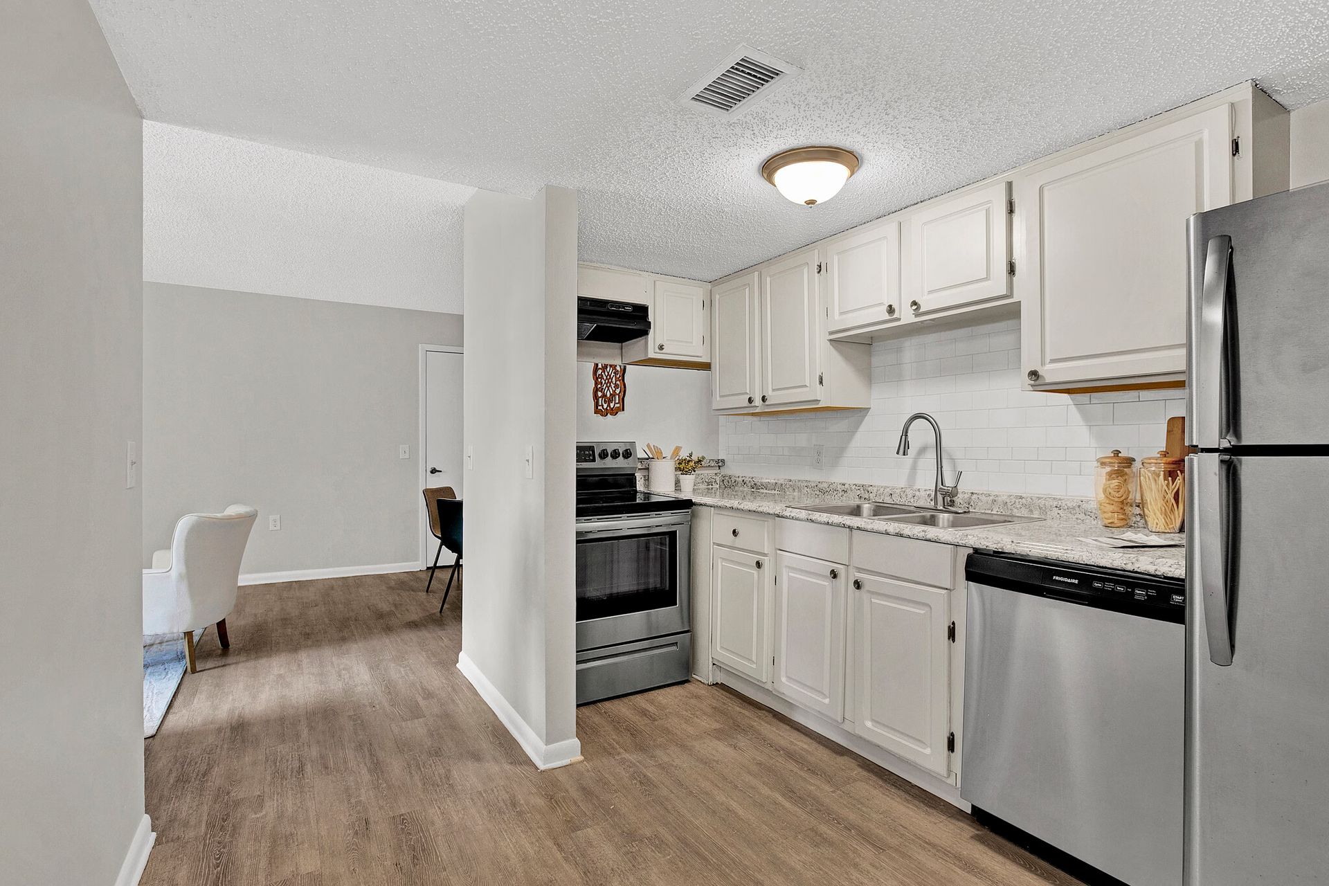 Kitchen with white cabinets, stainless steel appliances, and wooden flooring.